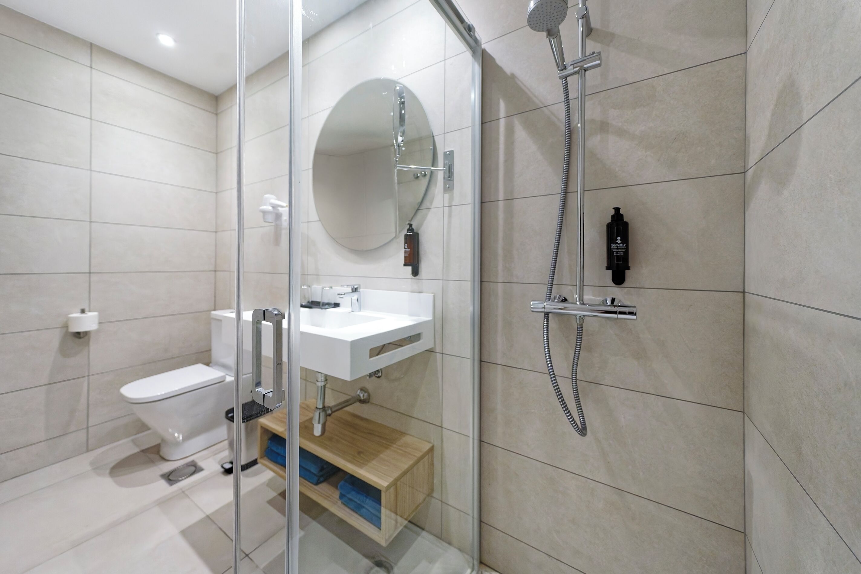 Et moderne badeværelse med brusekabine i glas, toilet, vask og spejl.