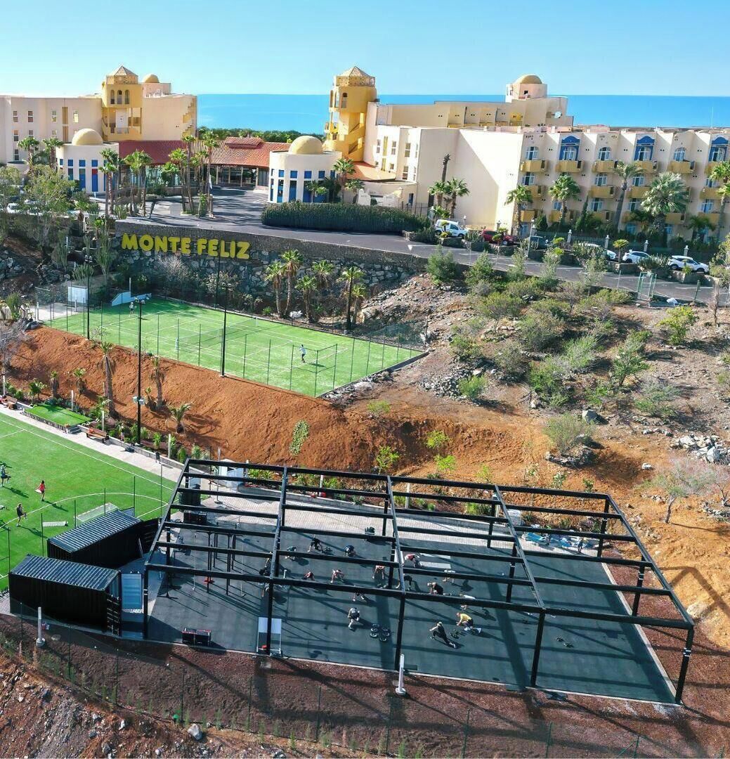 Una cancha de tenis con vistas al hotel Monte Feliz y al océano.