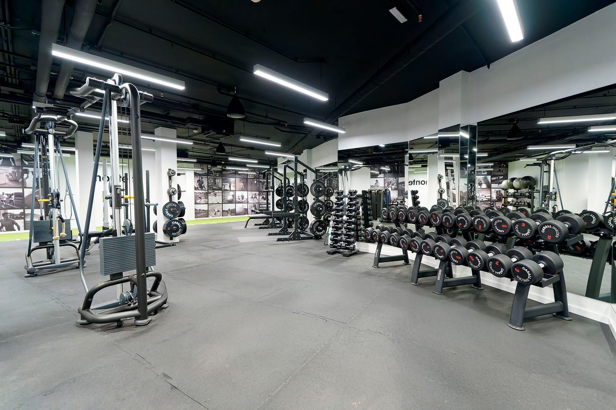 Et fitnesscenter med forskellig træningsudstyr, vægtstativer og spejle.