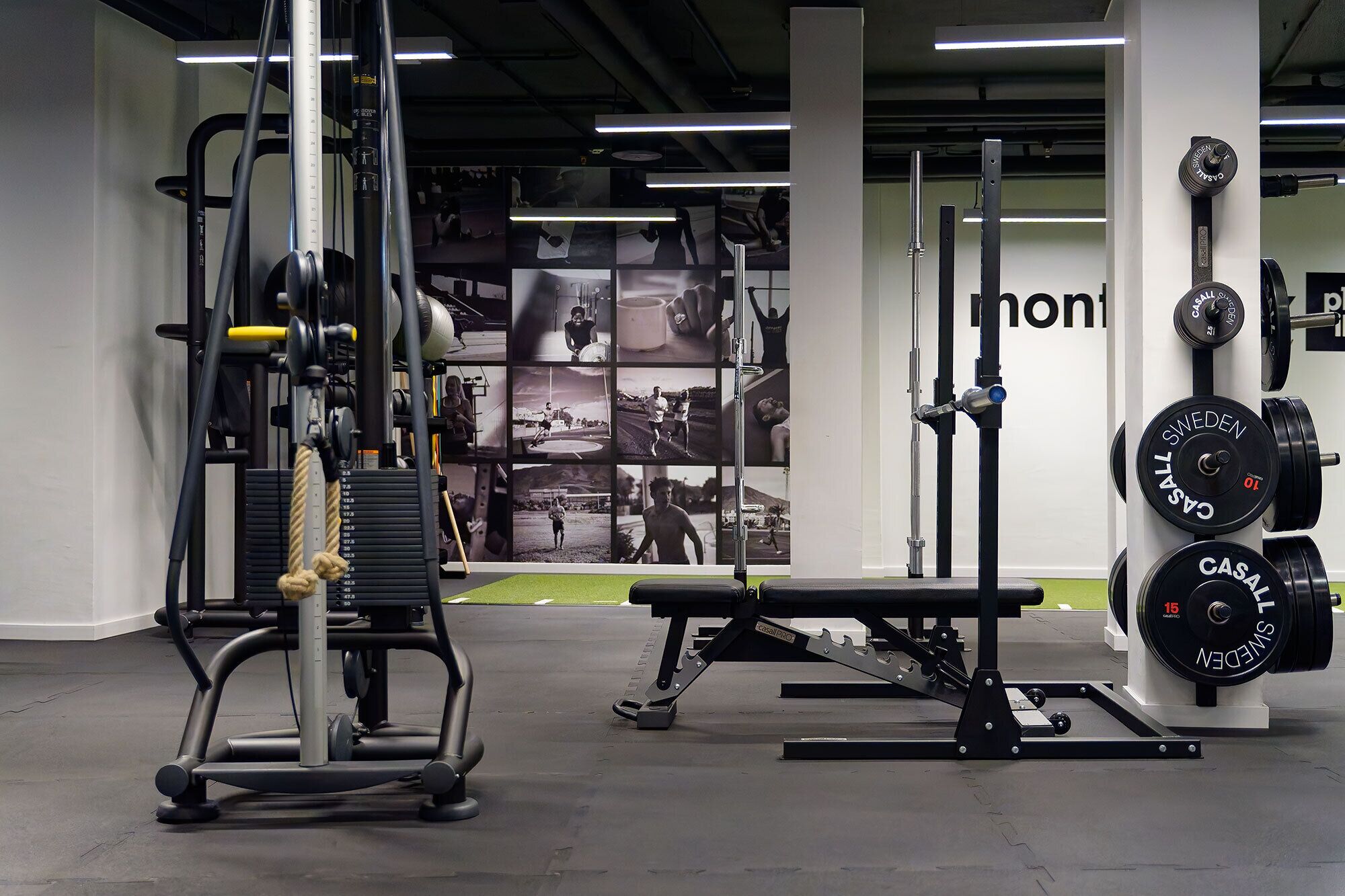 A gym with weightlifting equipment, a bench press, and a wall with motivational posters.