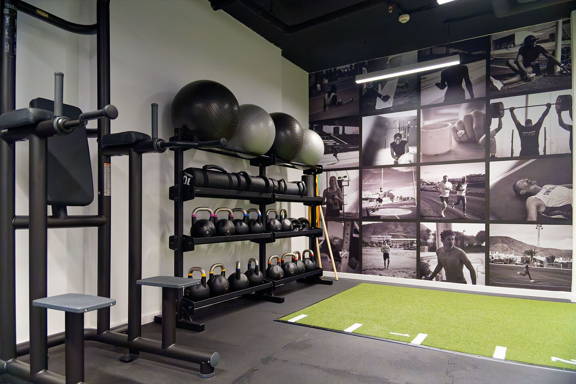 Ein Fitnessstudio mit Kraftgeräten, Kettlebells und einer Wand voller Fitnessfotos.