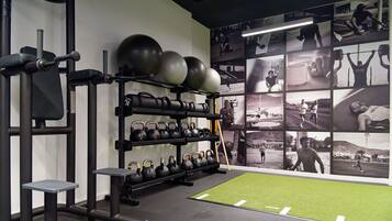 Ein Fitnessstudio mit Kraftgeräten, Kettlebells und einer Wand voller Fitnessfotos.