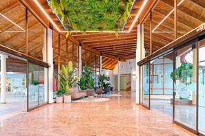 Un vestíbulo amplio con techo alto, vigas de madera e instalación colgante de plantas verdes.