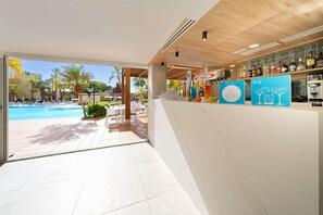 A modern bar area with a pool view, featuring a bar counter, seating area, and outdoor pool. - Sport Hotel Monte Feliz - powered by Playitas (San Bartolomé de Tirajana)