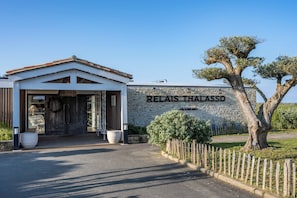 A building with a stone wall and a sign that reads 'RELAIS THALASSO.'