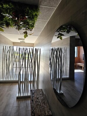 A modern interior with a curved mirror, abstract wall art, and a wooden bench.