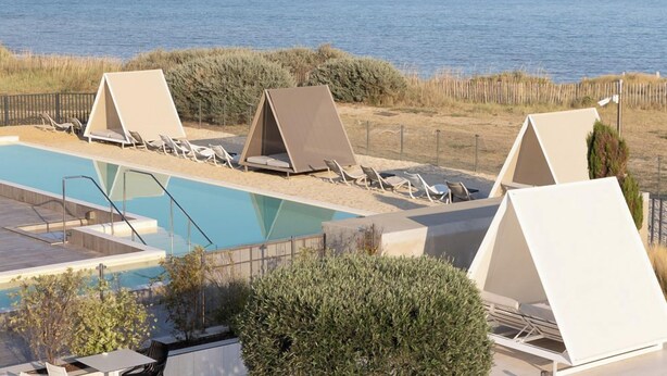 Un espace aménagé au bord de la piscine, avec des chaises longues et une vue sur la mer.