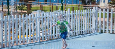 A water play area with a white fence and a view of the sea in the background.