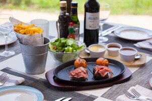 Una mesa preparada para una comida con ensalada, papas fritas, albóndigas y bebidas.