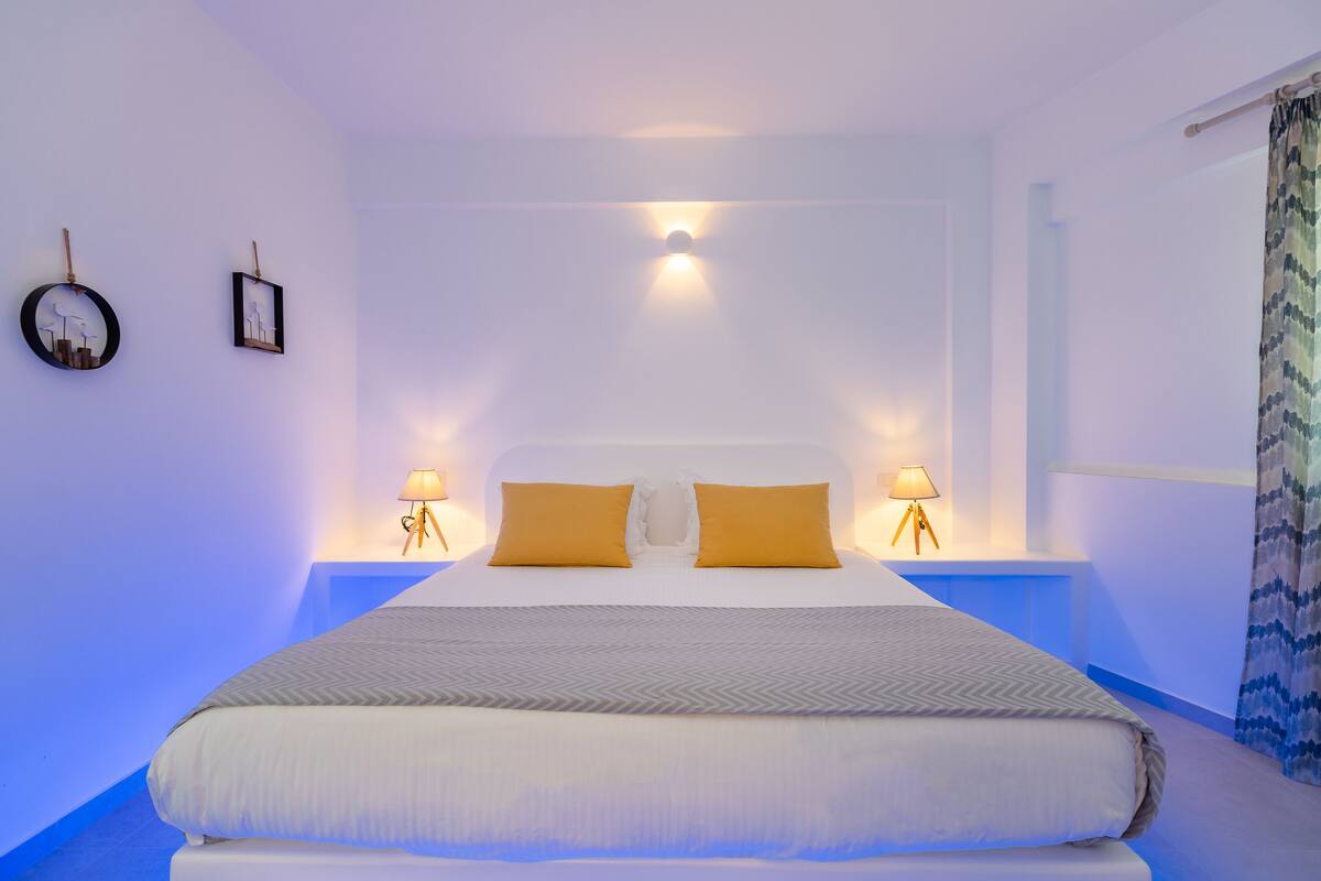 A neatly made bed with two pillows, a bedside table with a lamp, and wall art.