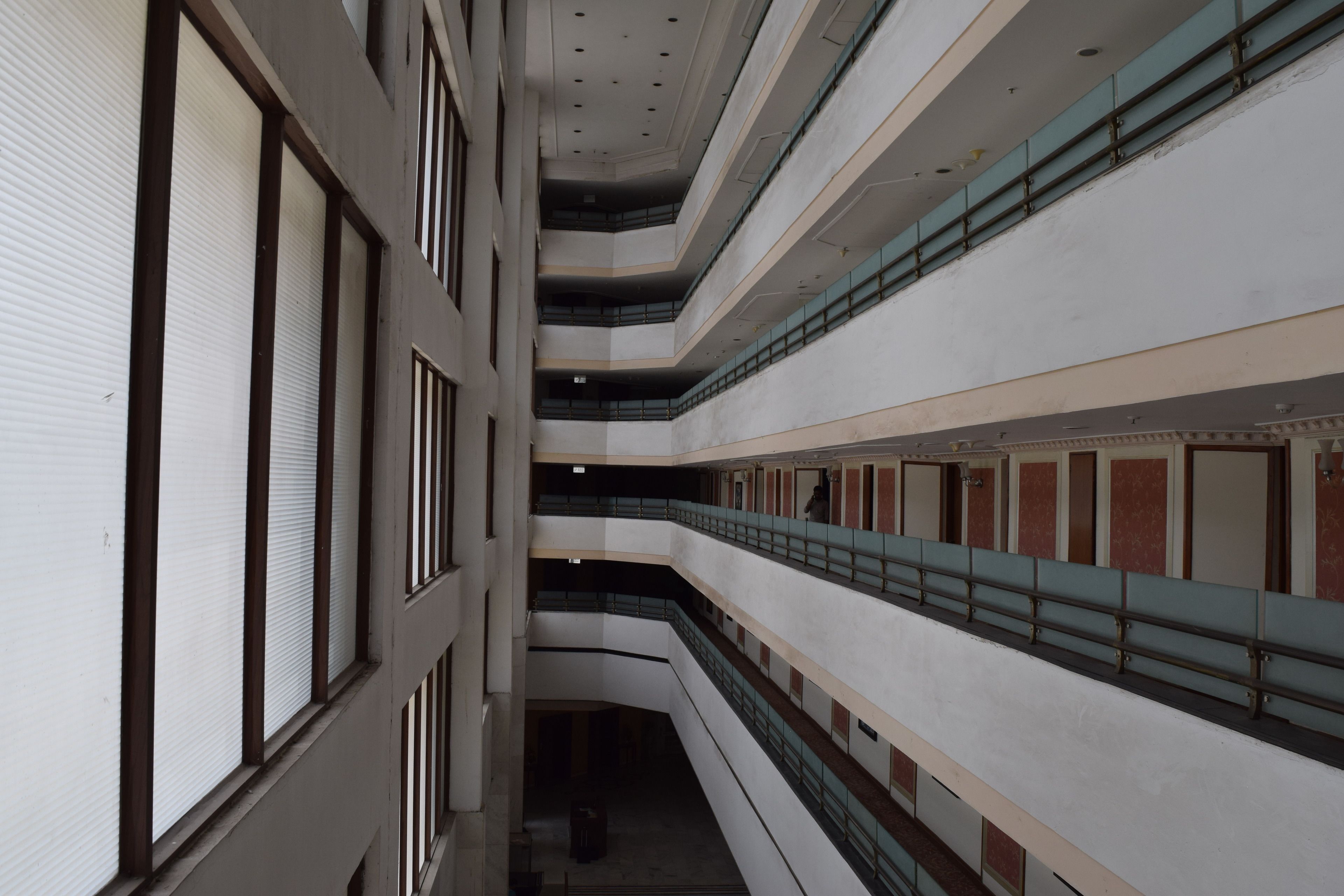 A multi-level interior with a central staircase, balconies, and a series of doors on the right side.