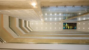 Un intérieur à plusieurs niveaux, agrémenté d’une grande fenêtre à vitraux au centre, d’un éclairage encastré et d’un plafond orné d’un motif géométrique.