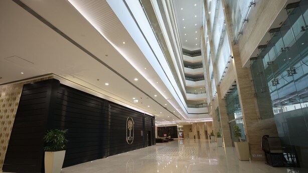 Un hall d’entrée spacieux et moderne, doté d’un haut plafond, de sols cirés et d’un comptoir d’accueil.