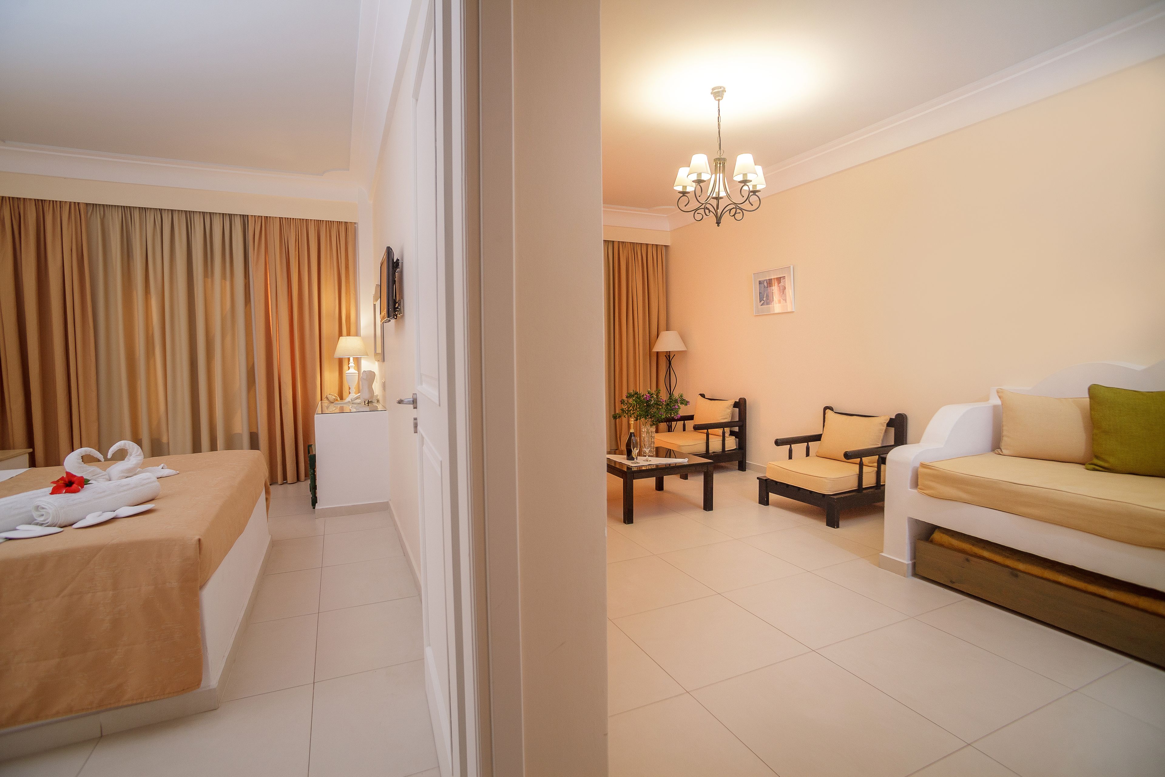 Une chambre d’hôtel avec un lit, un canapé, une table à manger et un lustre.