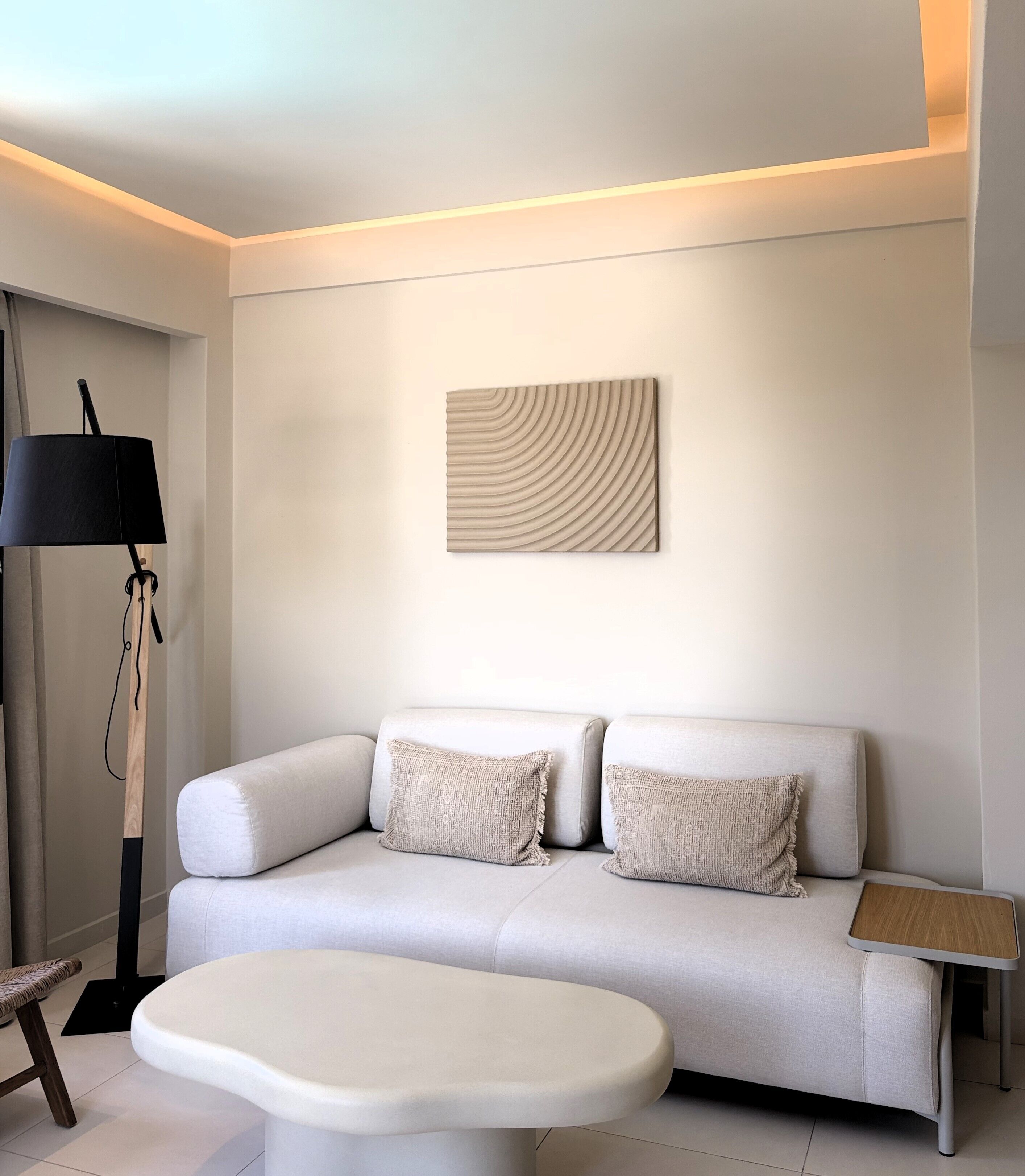Un salon moderne avec un canapé, une table basse, une lampe et une œuvre d’art murale.