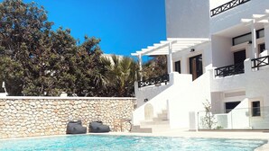 A swimming pool with a stone wall and white building in the background.