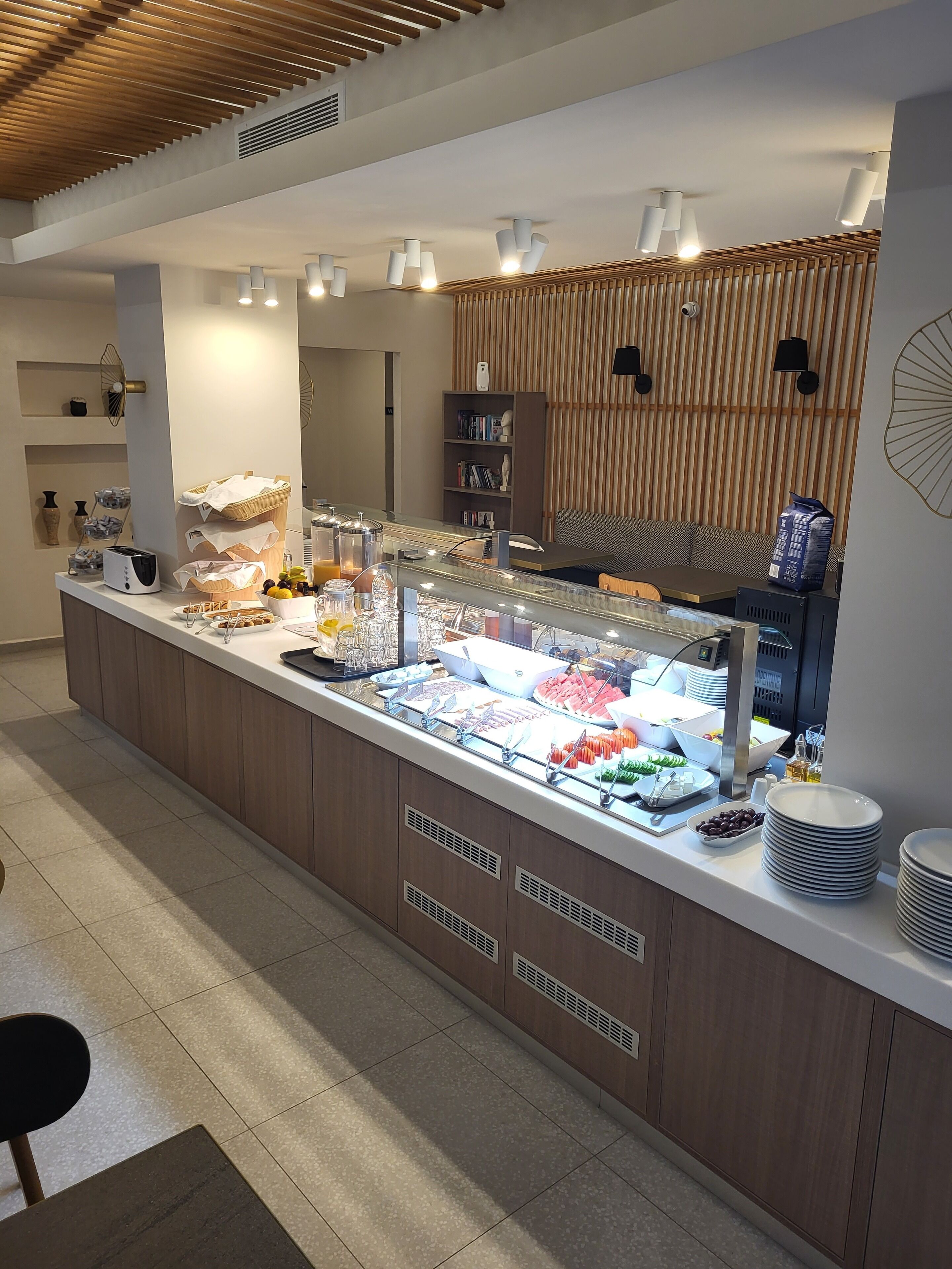 Un espace buffet proposant une variété de plats, un coin salon avec un canapé et une bibliothèque remplie de livres.