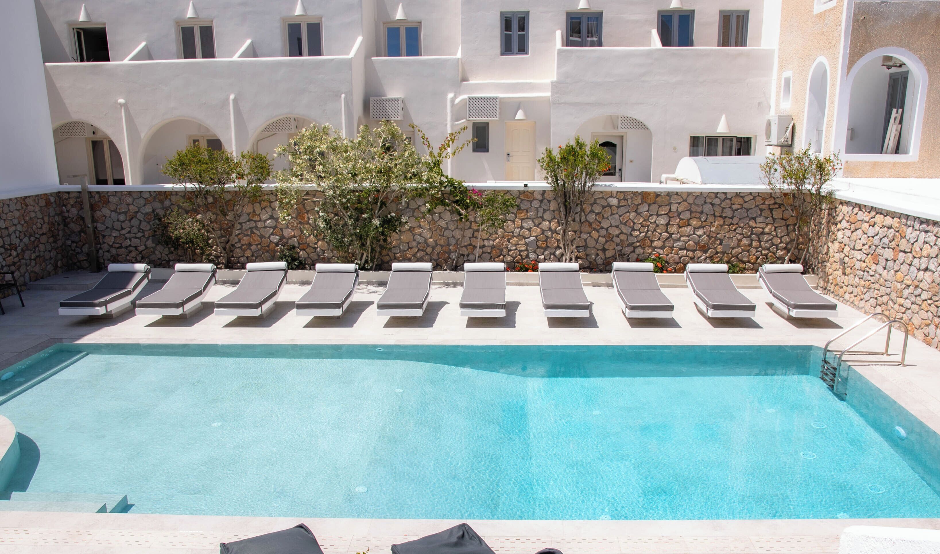 A poolside area with lounge chairs and a stone wall.