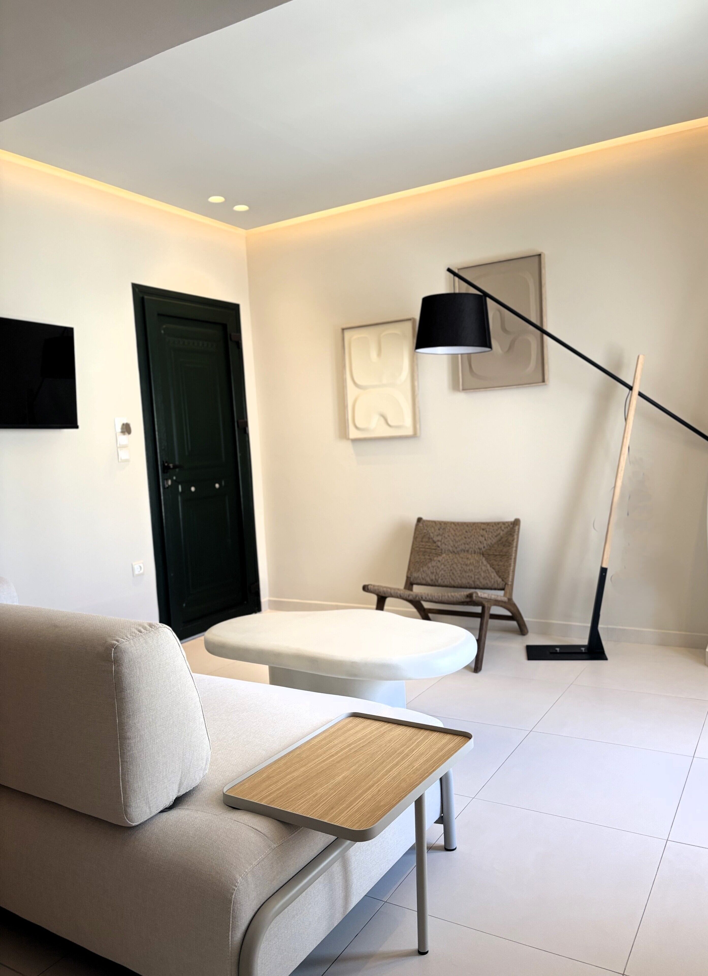 A modern living room with a sofa, a small table, a floor lamp, a chair, and artwork on the wall.