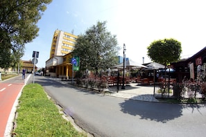 Una calle con un carril bici rojo, un café con terraza y un edificio amarillo con un letrero.