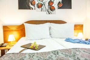 A neatly made bed with white linens, a wooden headboard, and a bedside table with a lamp. A small orchid and a notebook are on the bed. - Hotel Parc Sibiu (Sibiu)