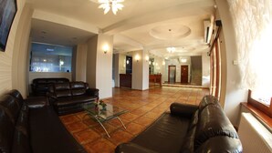 A spacious living area with leather sofas, a glass coffee table, and a kitchen in the background. - Hotel Parc Sibiu (Sibiu)
