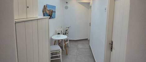 A narrow hallway with a skylight, a small table with chairs, and a door marked with the number 6.