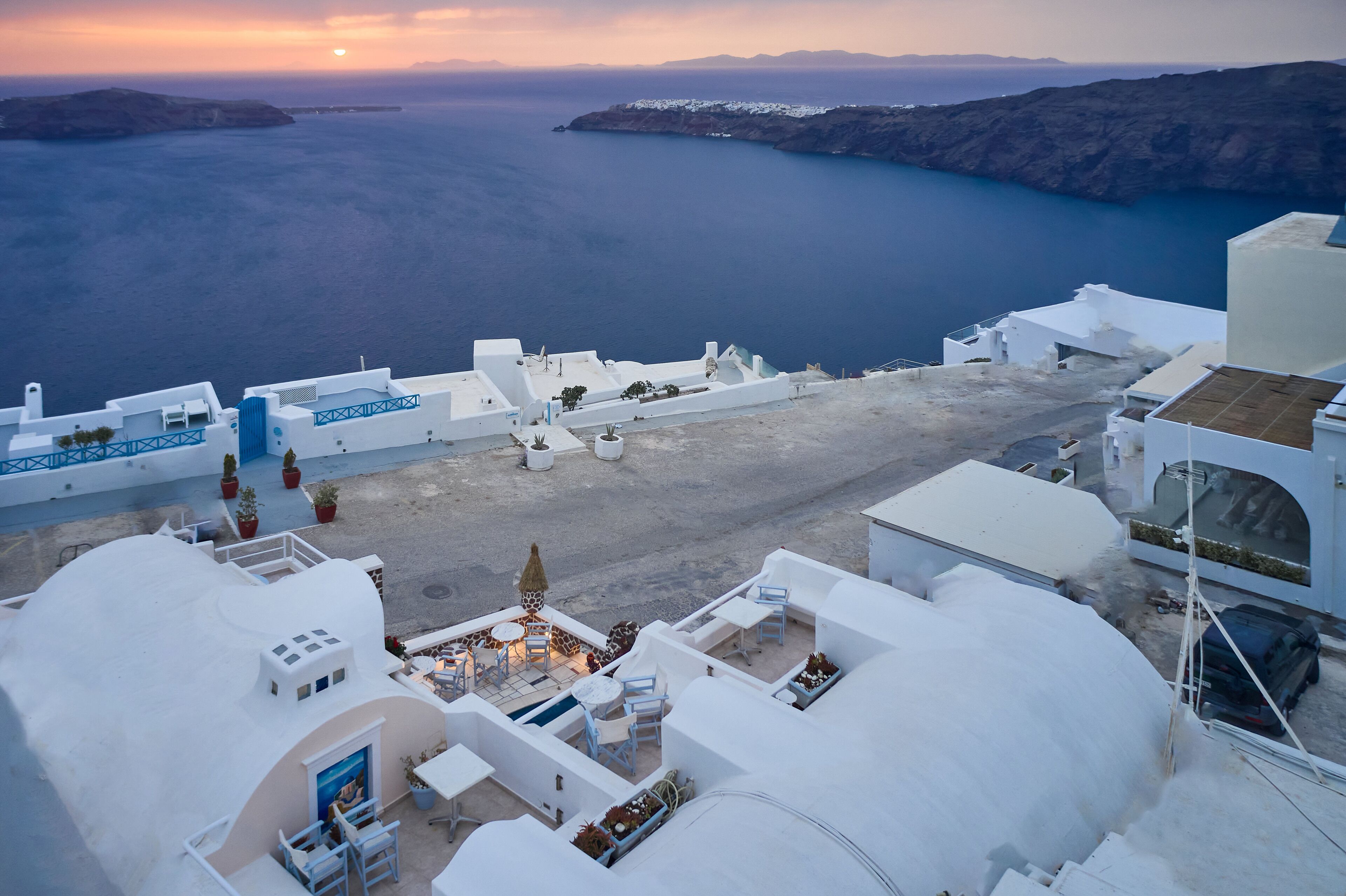 A white-roofed building with outdoor seating and a view of the sea.