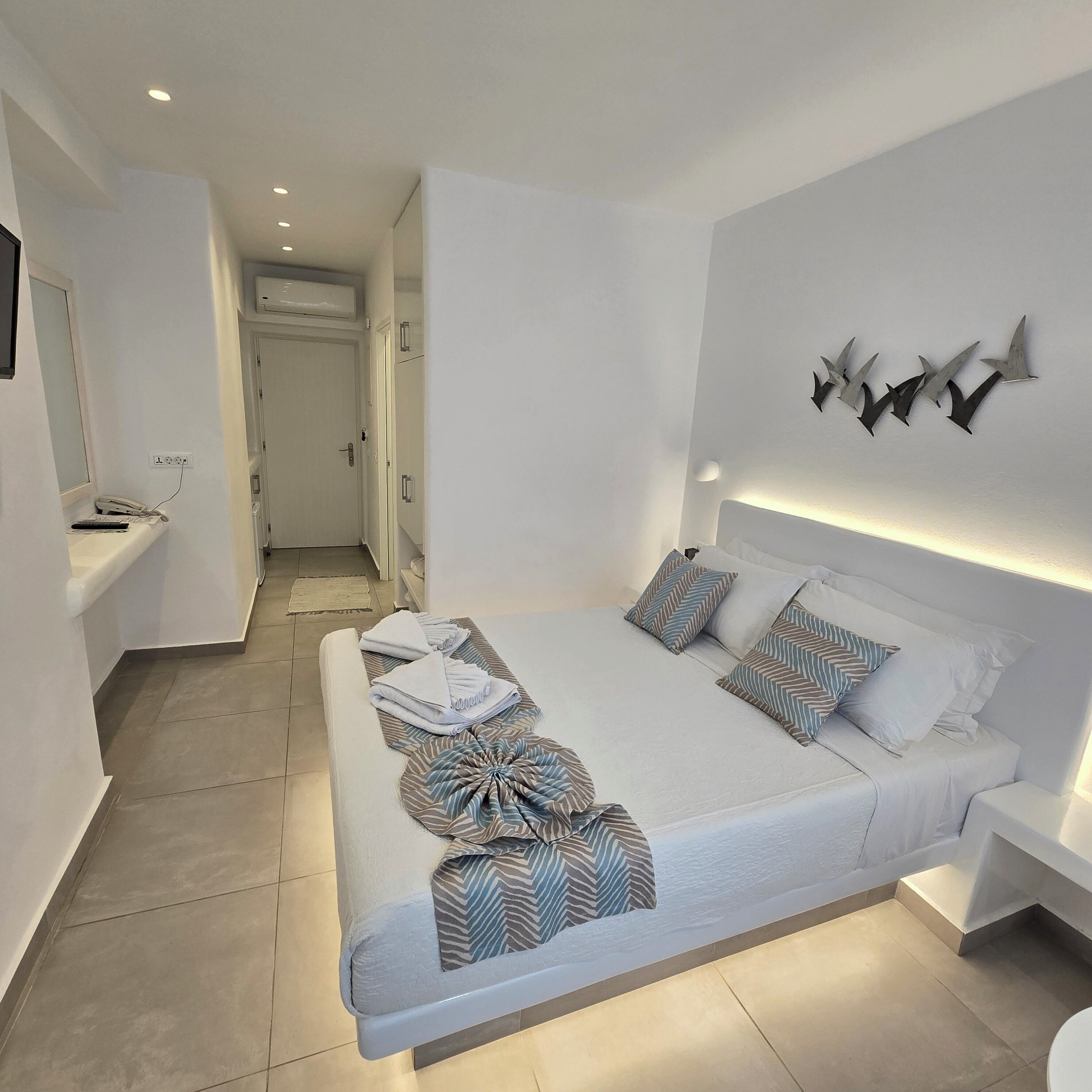 Un dormitorio moderno con una cama grande, mesitas de noche y una lámpara fijada a la pared.