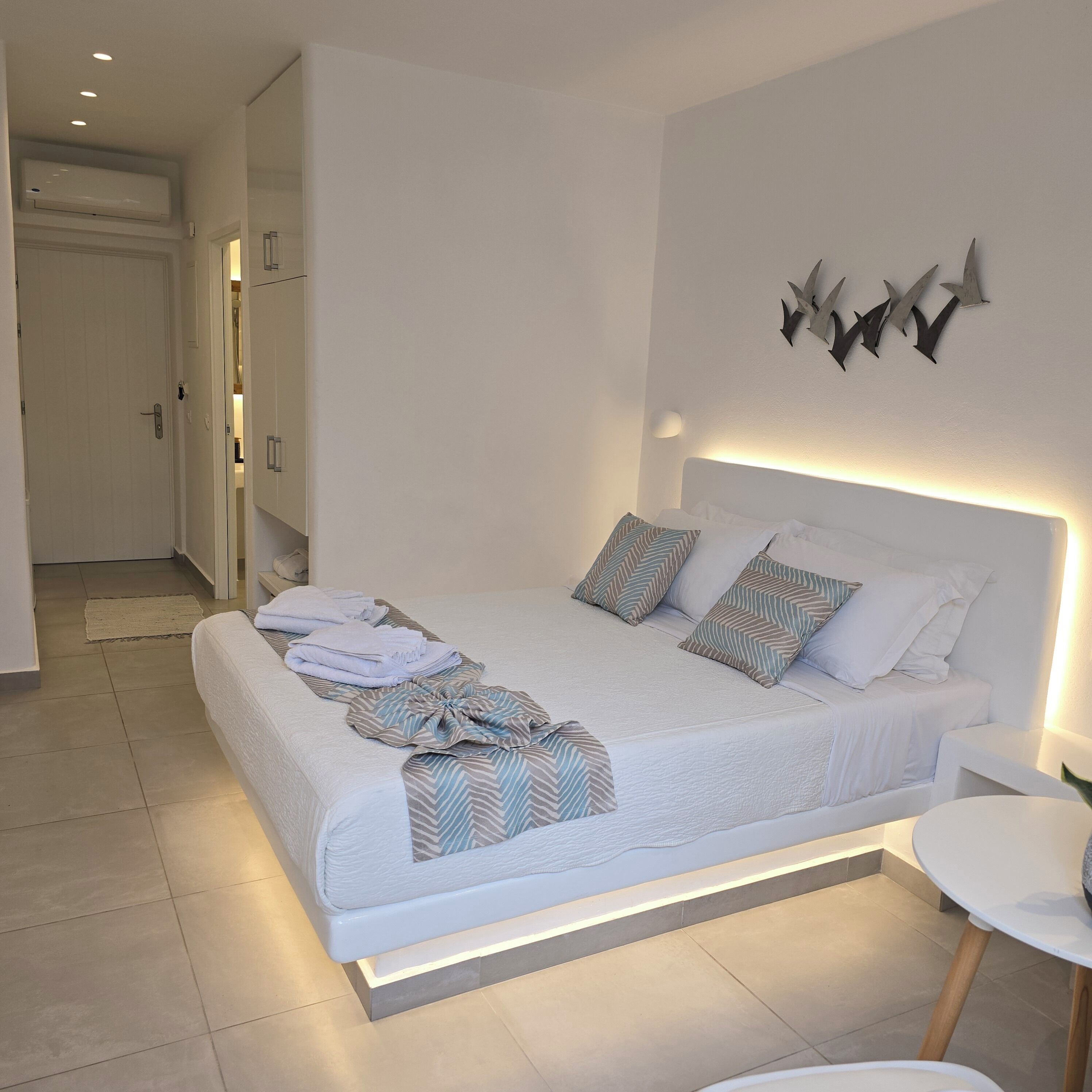 A modern bedroom with a large bed, bedside tables, and a wall-mounted light fixture.