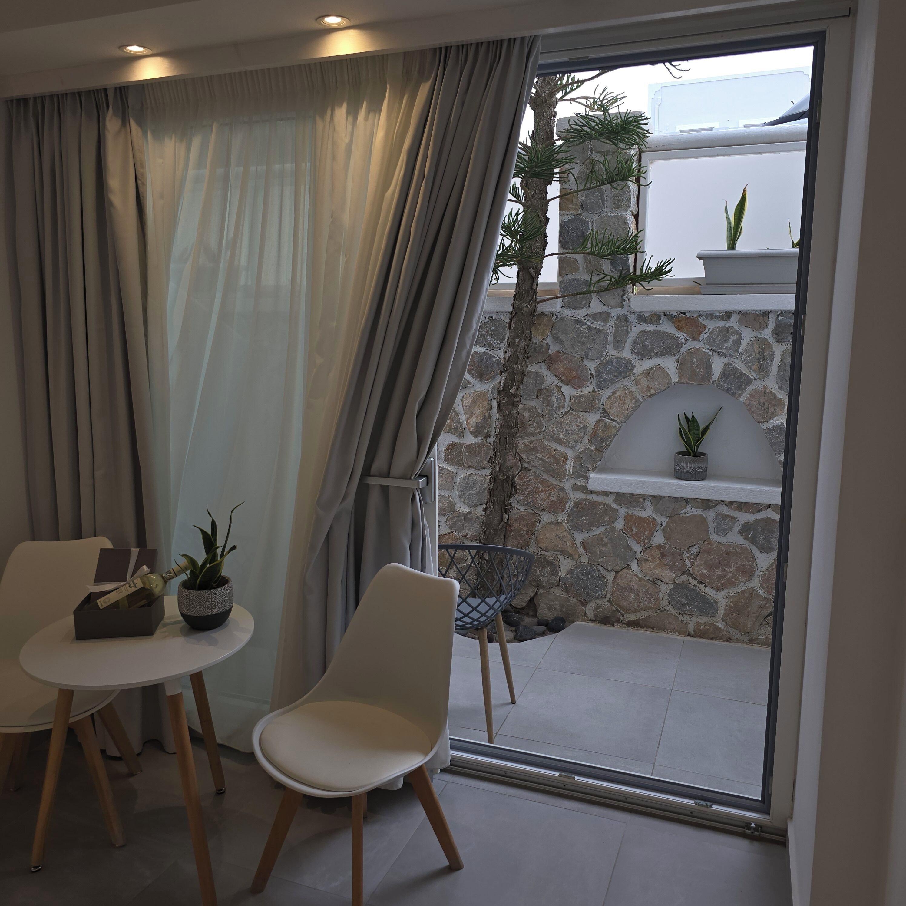 A modern room with a dining area, a stone wall, and a view of the sea.