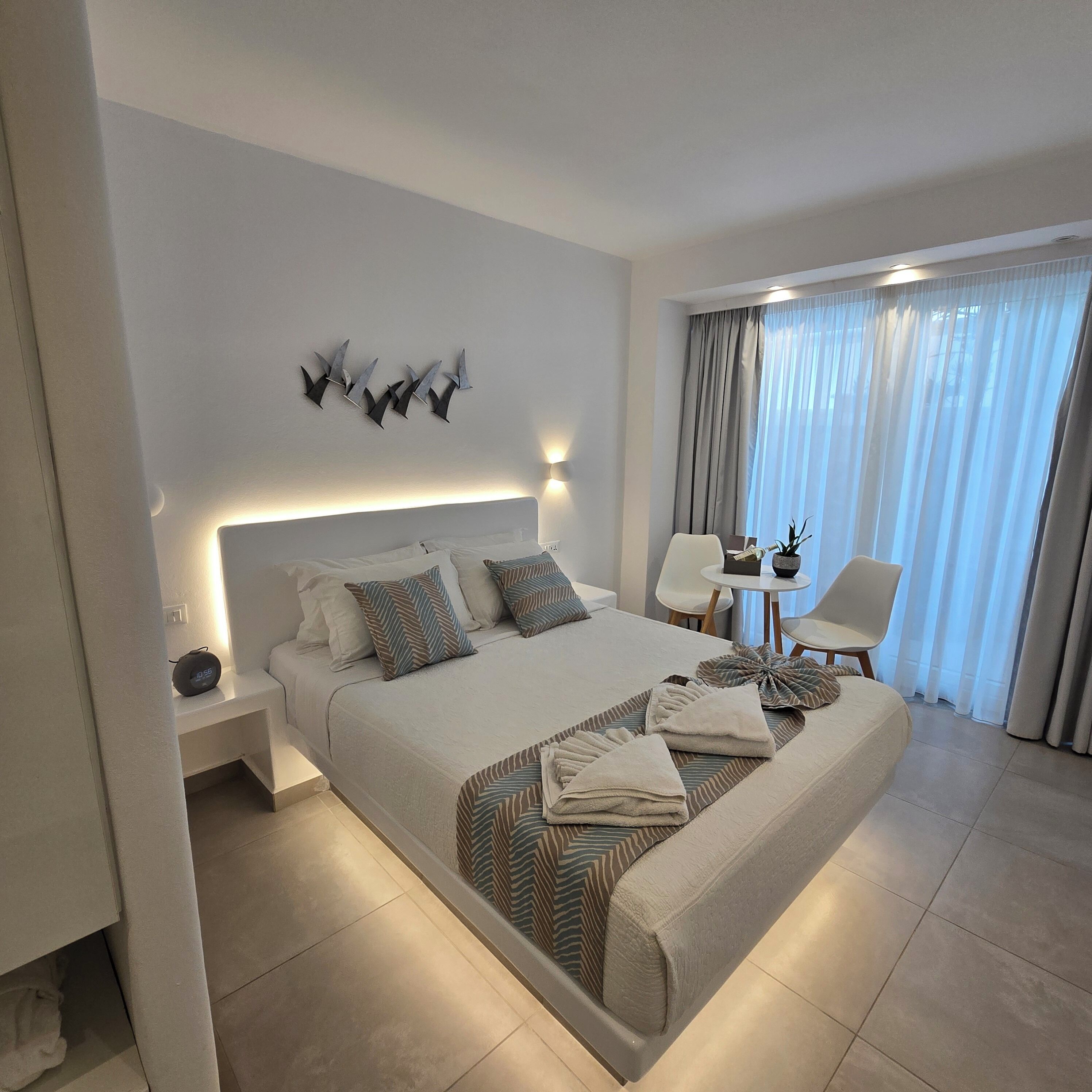 Una habitación de hotel moderna con una cama grande, mesitas de noche, un escritorio y una silla.