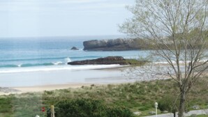A view from a window overlooking a beach, palm trees, and a road with street lamps. - Hotel Los Juncos (Noja)