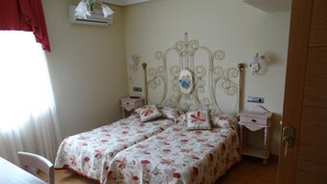 A bedroom with a bed, two bedside tables, a nightstand, a chair, and a wooden door. - Hotel Los Juncos (Noja)