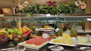 Un bufé con diversas frutas y verduras, incluyendo manzanas, plátanos, uvas y piñas.