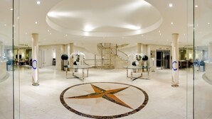 Un vestíbulo amplio con un suelo estampado con motivos de estrella, una escalera de caracol y un cartel que dice 'Lobby Bar' al fondo.