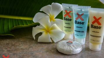 A collection of Base brand personal care products including shampoo, shower gel, and conditioner, arranged on a countertop with a white flower and a soap bar.