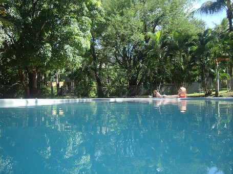 Una piscina al aire libre, sillones reclinables de piscina