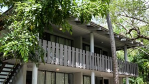 A two-story building with a balcony, large windows, and a tree in front. - Base Airlie Beach Resort - Hostel (Airlie Beach)