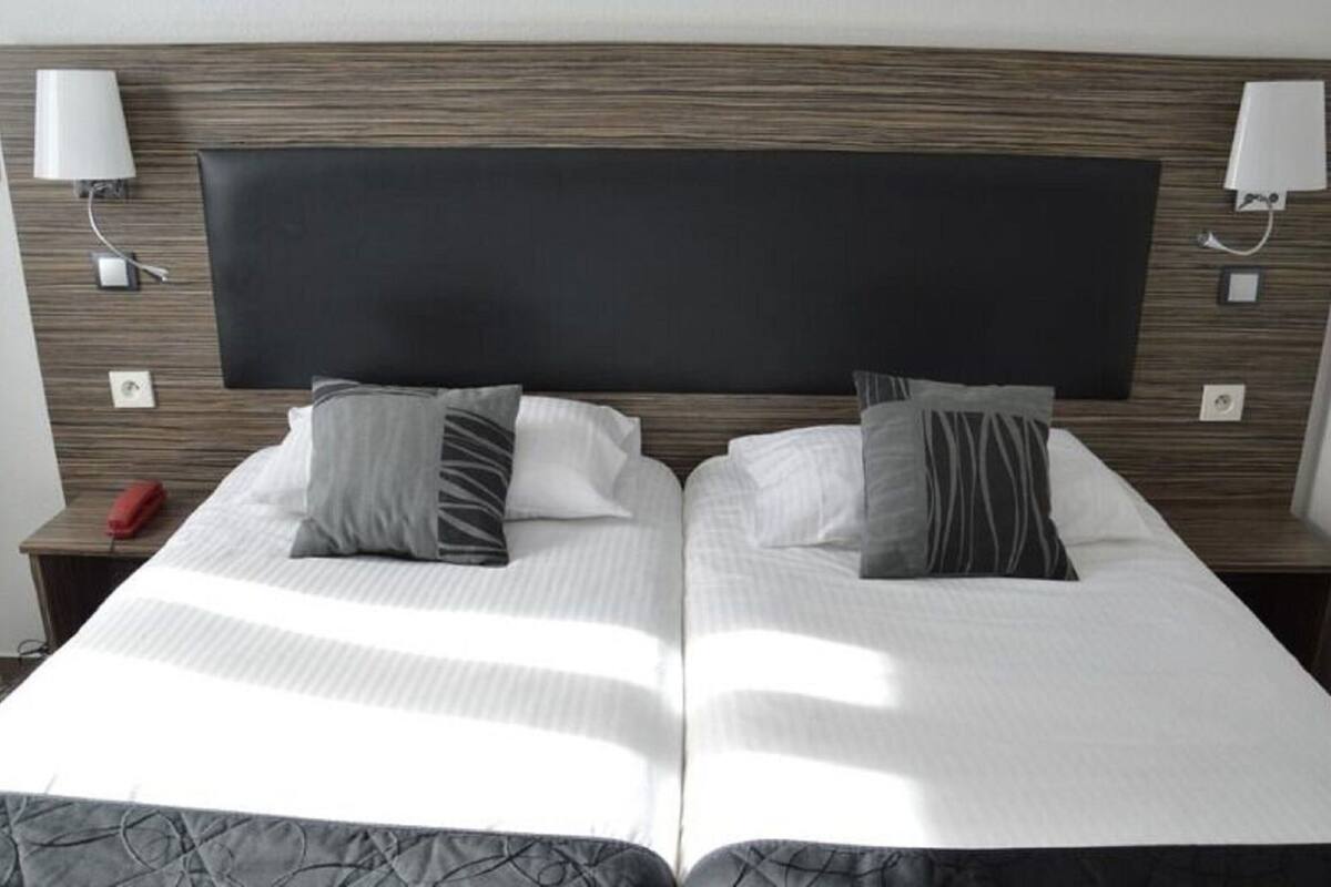 A double bed with a dark headboard, two bedside tables with lamps, and a red telephone on the left table.