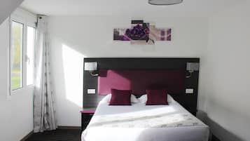 A hotel room with a large bed, a headboard, a bedside table, a lamp, and a window with curtains.