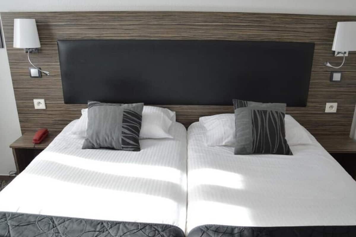 A double bed with a dark headboard, two bedside lamps, and a red telephone on the nightstand.