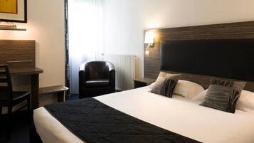 Une chambre d’hôtel avec un grand lit, un bureau, une chaise et un radiateur.