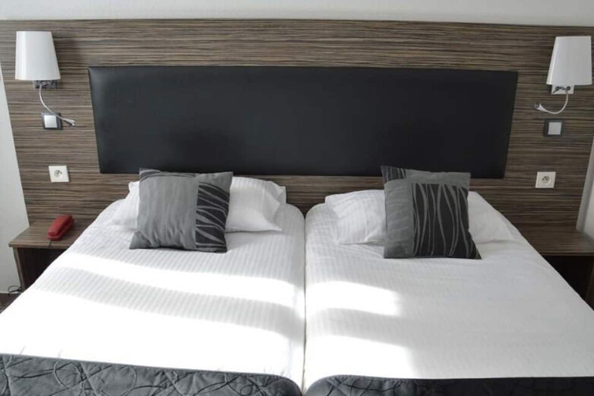 A double bed with a dark headboard, two bedside tables with lamps, and a red telephone on the left table.
