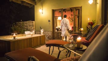 A spa area with a hot tub, candles, and a person in a robe.