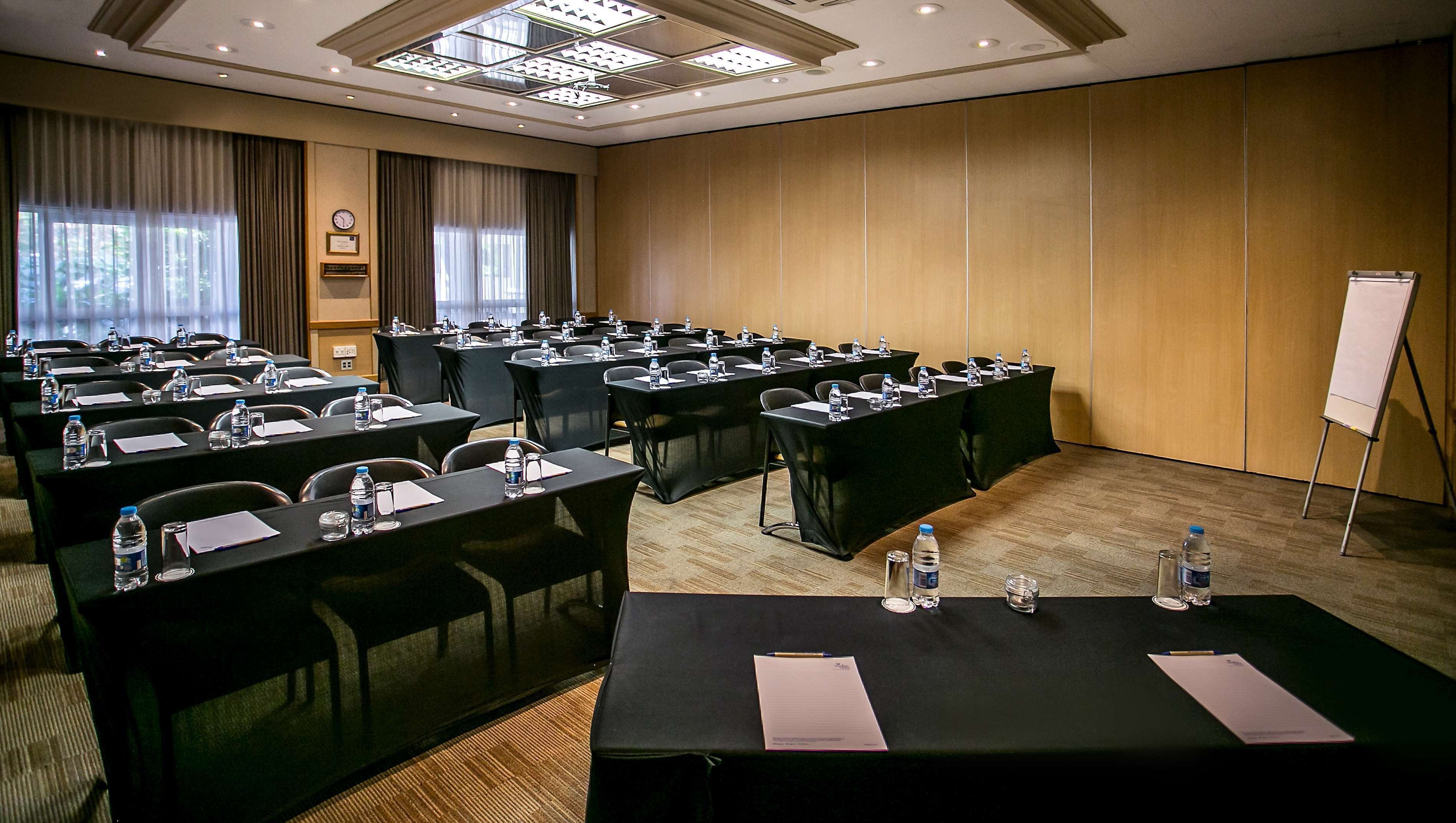 A conference room with multiple tables, chairs, water bottles, and a whiteboard.