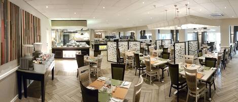 A modern dining area with multiple tables and chairs, a central counter, and decorative wall panels.