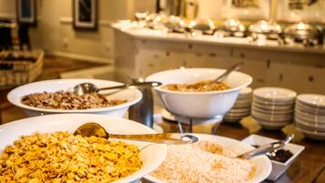 A buffet table with various food items in bowls, including cereal and rice.