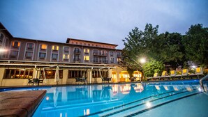 A hotel with a swimming pool, outdoor seating, and a building with multiple windows and balconies. - Garden Court O.R. Tambo International Airport (Kempton Park)
