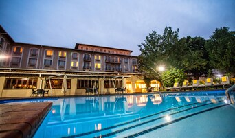 Una piscina al aire libre, sombrillas, sillones reclinables de piscina